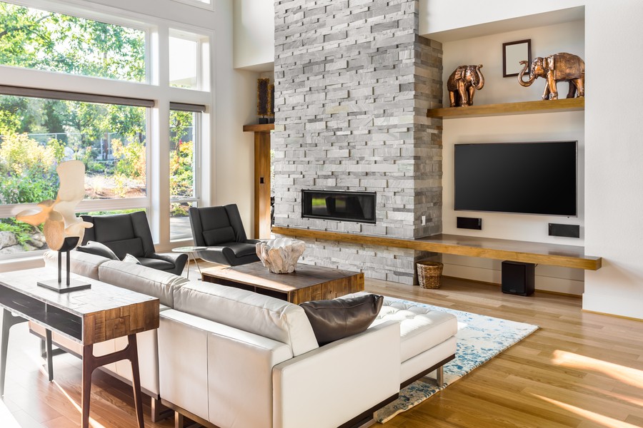 Image is of a living room with a fireplace, a luxury TV setup, and ceiling to floor windows.