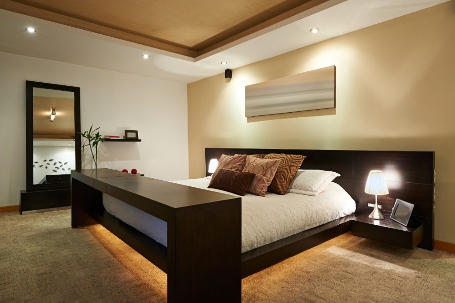 Modern bedroom with a large bed featuring brown and beige pillows.