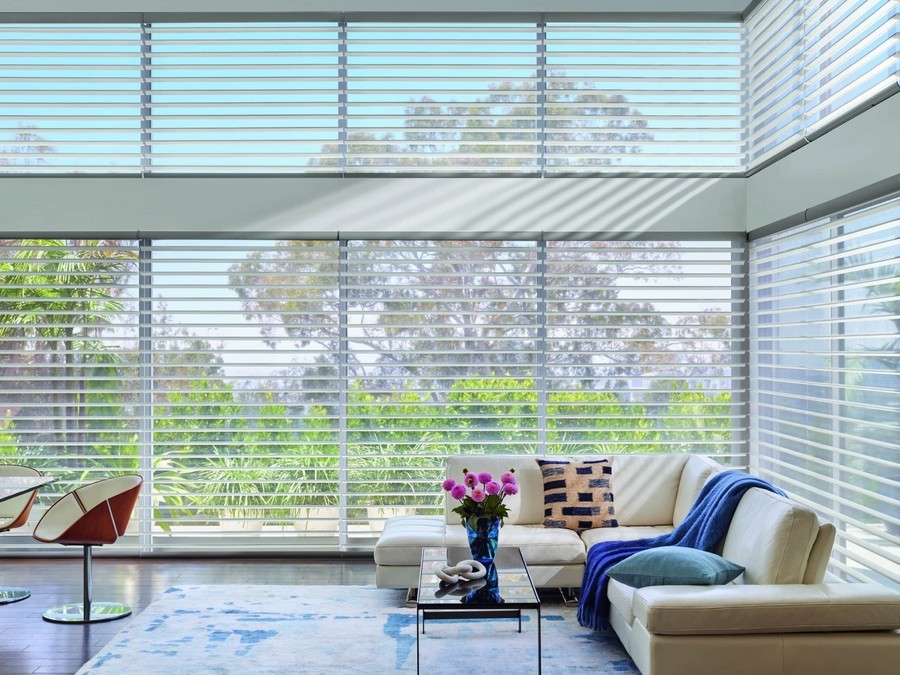 A living room with motorized blinds covering floor-to-ceiling windows.