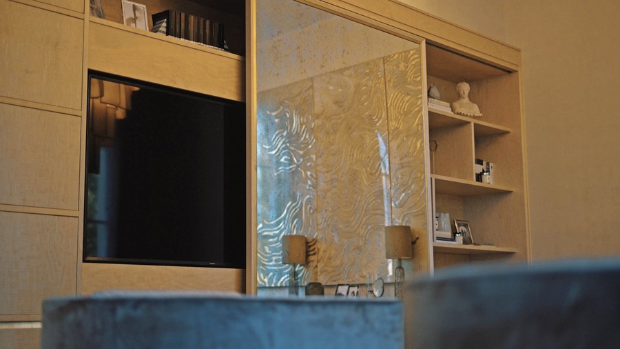 A mirror slides away to reveal a TV embedded in the cabinetry, an example of seamless audiovisual technology integration in a Cape Cod home. 